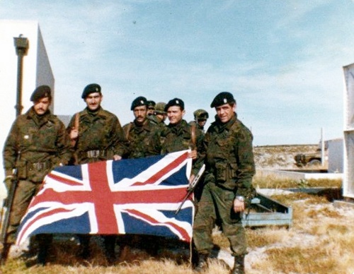 49 Cap.(pm) Luis Castagnari, junto a Suboficiales del GOE, al arriar la bandera inglesa el 2 de abril de 1982, en Pto. Argentino